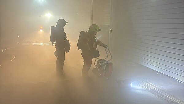 Zwei Feuerwehleute vor der verrauchten Garage