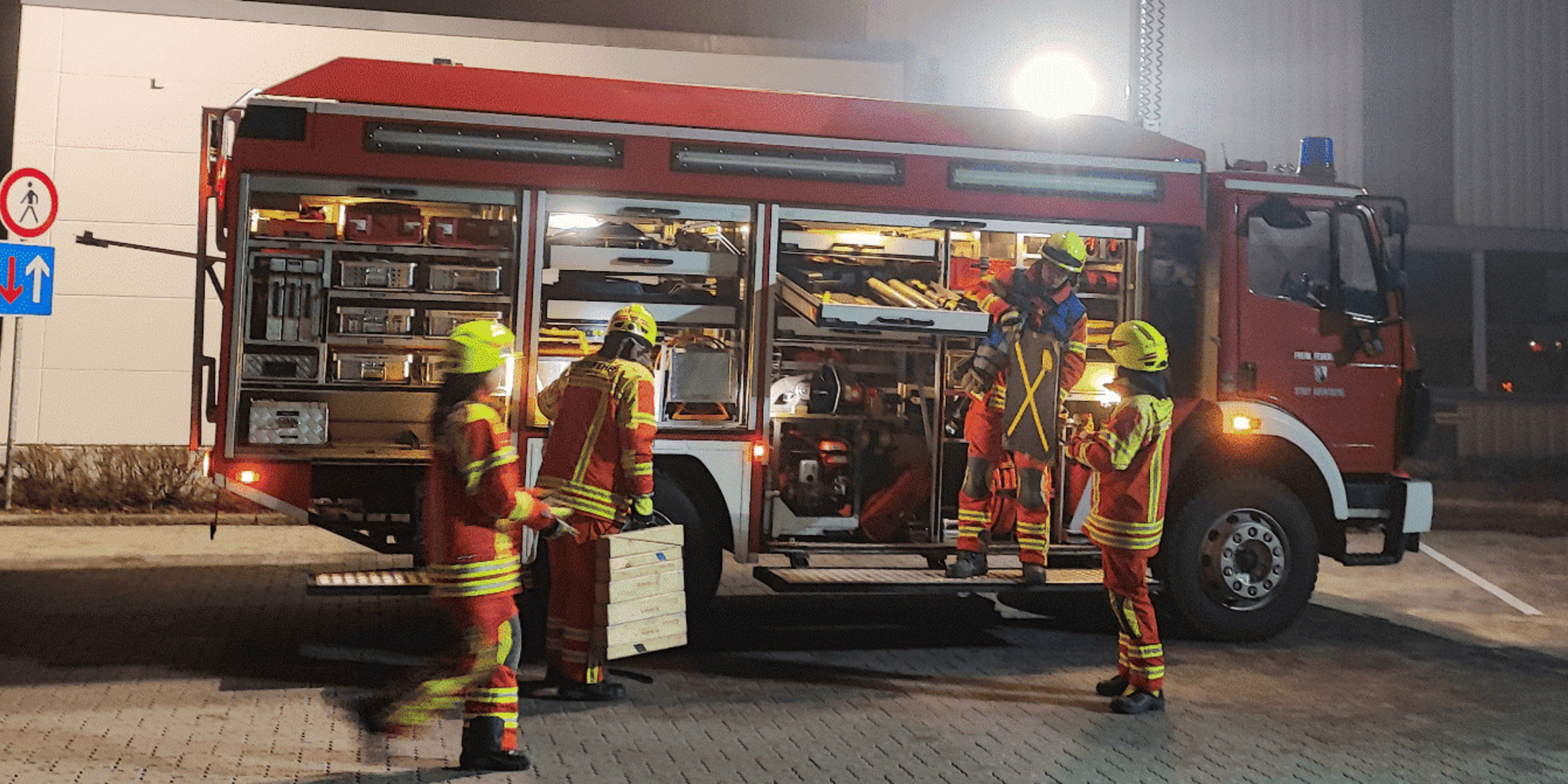 Feuerwehrleute vor dem Feuerwehrauto im Einsatz